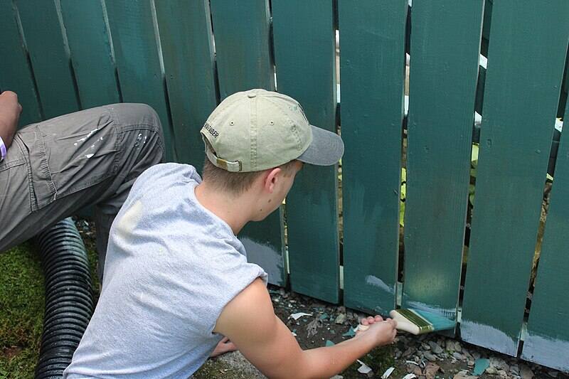 A man painting a fence